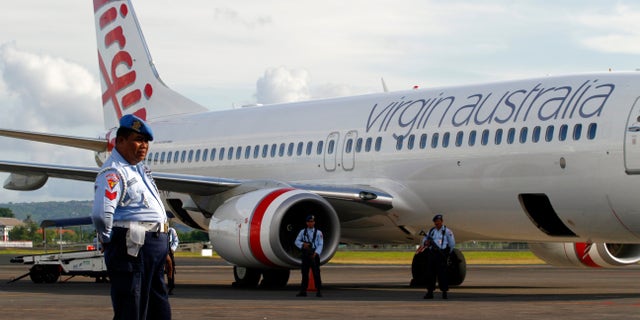 April 25, 2014 - Indonesian Air Force personnel stand guard by a Virgin Australia airplane in Bali, Indonesia. A drunken passenger who caused a hijack scare on a Virgin Australia flight by trying to break into the cockpit was arrested Friday after the plane landed on Bali, officials said.