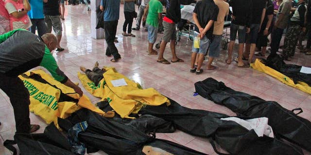 People wait to identify the bodies of their relatives among the victims of a karaoke fire, at a hospital in Manado, North Sulawesi, Indonesia, Sunday, Oct. 25, 2015. More than a dozen of people were killed in the fire that raced through a packed karaoke bar early Sunday on Indonesia's Sulawesi island, and tens others were hospitalized for smoke inhalation. (AP Photo/Ronny Adolof Buol)