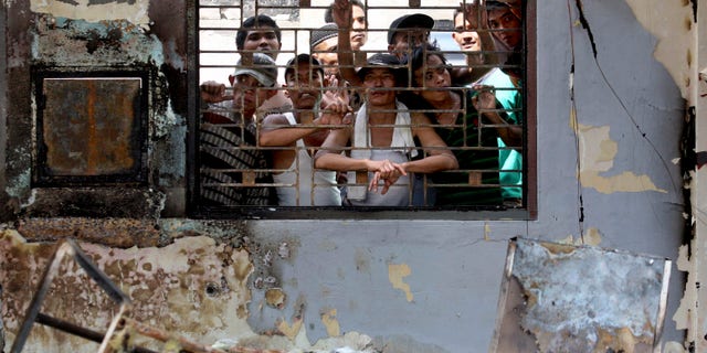 July 12, 2013 - Inmates look out from inside a burned office at Tanjung Gusta prison following a prison riot in Medan, North Sumatra, Indonesia. Security forces regained control of the crowded prison where inmates set fires and started a deadly riot that left five people dead and hundreds of prisoners, including convicted terrorists, on the loose, officials said.