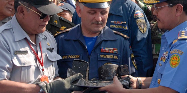 May 16, 2012: Chief of Indonesian National Transportation Safety Board Tatang Kurniadi, left, National Search and Rescue Agency head Daryatmo, right, and an unidentified Russian investigator inspect the burnt cockpit voice recorder of a Sukhoi Superjet-100.