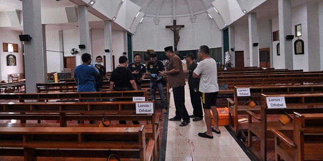 Police officers investigate inside St. Lidwina Church following an attack in Sleman, Yogyakarta province, Indonesia, Sunday, Feb. 11, 2018. Police shot a sword-wielding man who attack the church during a mass, injuring a number of people including a German priest. The reason for the attack Sunday morning was not immediately clear. (AP Photo/Slamet Riyadi)