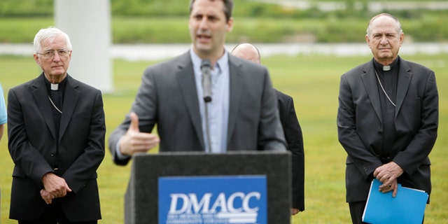Bishop Martin Amos, of the Diocese of Davenport, left, and Bishop Richard Pates, of the Diocese of Des Moines, right, listen to Lonnie Ellis speak during a news conference, Thursday, July 2, 2015, in Ankeny, Iowa. Roman Catholic leaders in Iowa are calling for presidential candidates to focus on the environment and income inequality in 2016. (AP Photo/Charlie Neibergall)