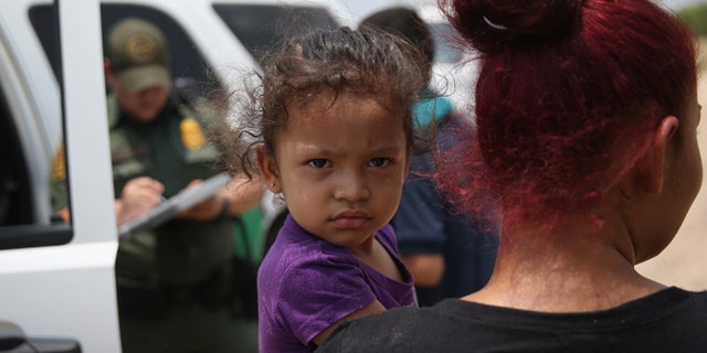 MISSION, TX - JULY 24: A mother and child, 3, from El Salvador await transport to a processing center for undocumented immigrants after they crossed the Rio Grande into the United States on July 24, 2014 in Mission, Texas. Tens of thousands of immigrant families and unaccompanied minors have crossed illegally into the United States this year and presented themselves to federal agents, causing a humanitarian crisis on the U.S.-Mexico border. (Photo by John Moore/Getty Images)