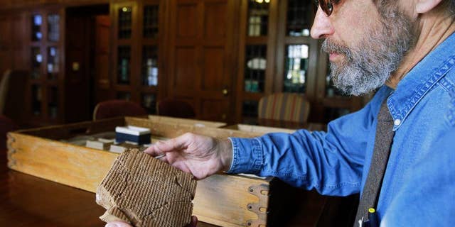 FILE - In this Oct. 16, 2008 file photo, Matt Stolper, director of the Persepolis Fortification Archive at the University of Chicago's Oriental Institute, examines a tablet that is part of a collection that provide a top-to-bottom look at life in the Persian empire 2,500 years ago. On Friday, March 28, 2014, a federal judge in Chicago ruled that survivors of a 1997 terrorist attack blamed partly on Iran can't seize museum pieces in U.S. collections to help pay a $412 million judgment against Iran. The ruling stems from a long-running legal battle that museum officials elsewhere watching closely. They feared their own collections could be put at risk if the judge had allowed collections of Persian antiquities at Chicago's Field Museum and the University of Chicago to be seized. (AP Photo/M. Spencer Green, File)