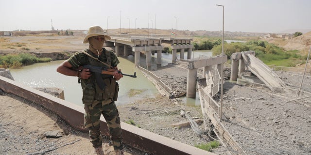 Sept. 20, 2014 - A Kurdish Peshmerga fighter stands guard near the Khazer bridge, on a road between Mosul and Irbil, Iraq, destroyed by ISIS fighters in clashes with Kurdish forces. The destruction of the bridge cut off the road for civilians to Mosul and nearby Christian villages.