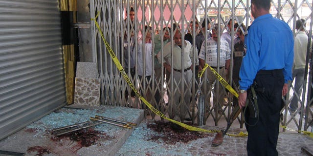 Oct. 27: An Iraqi policeman stands guard and people take in the scene the morning after gunmen stormed a jewelry store in Kirkuk, 180 miles north of Baghdad, Iraq.