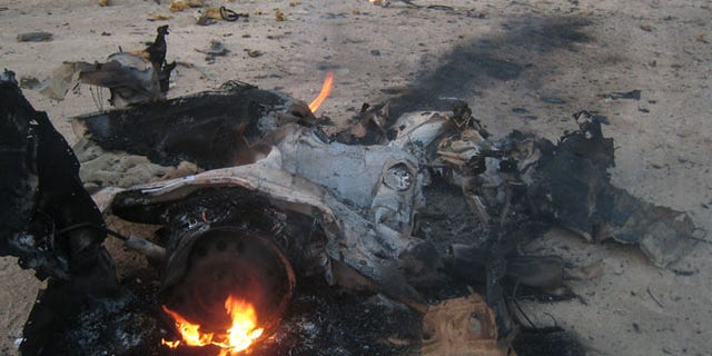 Security forces and civilians inspect the scene of a car bomb attack north of Baghdad, Iraq, Friday July 26, 2013. Attacks on civilians and government forces have escalated across Iraq recently. More than 3,000 people have been killed since April.