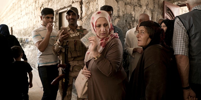Iraqis women enter a polling site to cast their ballots in the parliamentary elections in Mosul, Iraq.