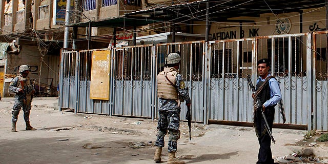Sept. 30, 2010: Iraqi policemen stand guard outside the branch of the state-run al-Rafidain bank in southwestern Baghdad, Iraq.
