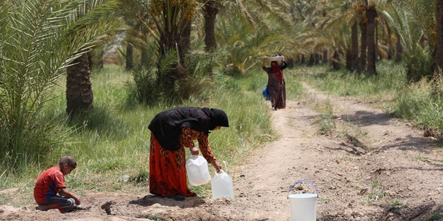 Iraqis displaced by conflict collect water at al-Takia refugee camp in Baghdad, Iraq, Thursday, July 30, 2015.