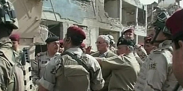 In this image made from television, Iraqi Defense Minister Abdul-Qadir al-Ubaidi , center, inspects the site of a suicide attack accompanied by soldiers at a military headquarters in Baghdad, Sunday, Sept. 5, 2010. Suicide bombers hit a Baghdad military headquarters on Sunday and killed dozens of people, two weeks after an attack on the same site pointed to the failure of Iraqi forces to plug even the most obvious holes in their security. (AP Photo/APTN)