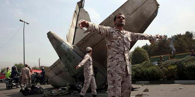 Aug. 10, 2014: Iranian Revolutionary Guards prevent the media from approaching the wreckage of a passenger plane crash near the capital Tehran, Iran. (AP)