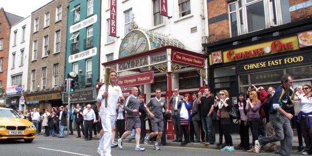June 6, 2012: Irish boxer Kenny Egan, 30, carries the Olympic torch past the Olympia Theater as he runs through central Dublin, Ireland.