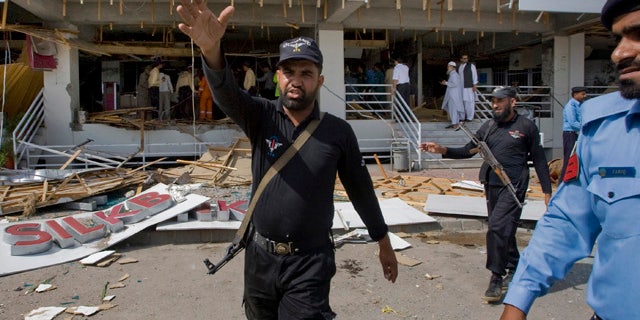 June 13: A Pakistan police officer gestures towards the media from the site of suicide bombing in Islamabad, Pakistan.