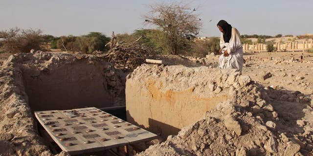 A mausoleum caretaker prays at a damaged tomb in Timbuktu, in 2014.