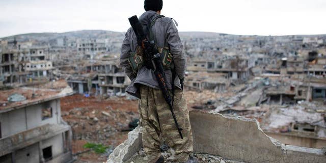 FILE - In this Jan. 30, 2015 file photo, a Syrian Kurdish sniper looks at the rubble in the Syrian city of Ain al-Arab, also known as Kobani. Foreign fighters are streaming in unprecedented numbers to Syria and Iraq to battle for the Islamic State or other U.S. foes, including at least 3,400 from Western nations and 150 Americans, U.S. intelligence officials conclude. In all, more than 20,000 fighters have traveled to Syria from more than 90 countries, top intelligence officials will tell Congress this week. (AP Photo, File)