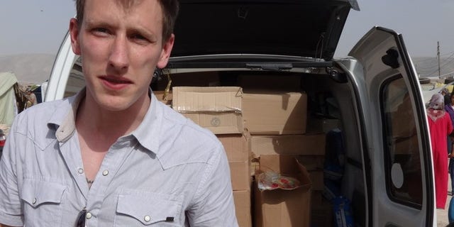 FILE - This undated file photo provided by the Kassig Family shows Peter Kassig standing in front of a truck filled with supplies for Syrian refugees. A new graphic video purportedly produced by Islamic State militants in Syria released Sunday Nov. 16, 2014 claims U.S. aid worker Kassig was beheaded. (AP Photo/Courtesy Kassig Family, File)