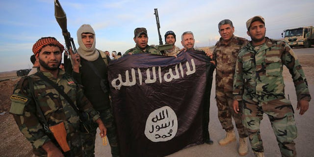 FILE: Nov. 23, 2014: Iraqi Shite fighters with an Islamic State flag that they pulled down on the front line in Jalawla, Diyala province of Iraq.