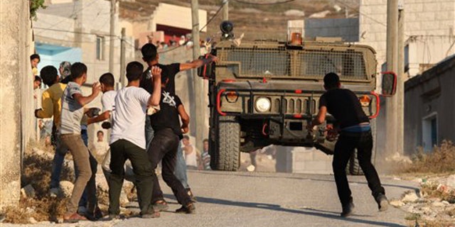 July 3, 2011: Palestinian youths hurl stones at Israeli troops during clashes over farming land between the Jewish settlement of Yitzhar and the nearby West Bank village of Asira, near Nablus.