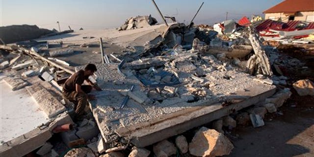 Sept. 5, 2011: A Jewish settler sits on the rubble of a house demolished by the Israeli authorities in the West Bank settlement of Migron near the Palestinian city of Ramallah.