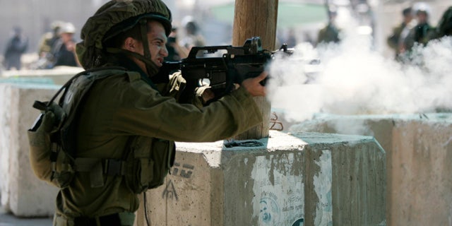 Aug. 26, 2011: An Israeli soldier fires tear gas canisters at Palestinian protesters during a protest march at the Qalandia checkpoint between the West Bank city of Ramallah and Jerusalem.