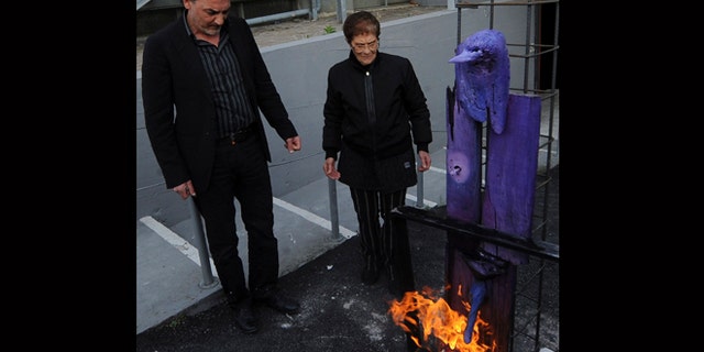 April 18, 2012: Antonio Manfredi, left, director of the Casoria Contemporary Art Museum, and Italian artist Rosaria Matarese burn one of Matarese's creations in front of the museum, near Naples.