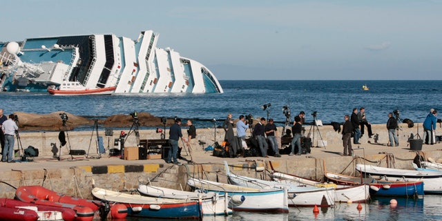 Jan. 20, 2012: Media crews stand on the harbor wall facing the Costa Concordia cruise liner off the tiny Tuscan island of Giglio, Italy.