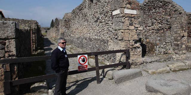 A man stands by the area where thieves pried off a chunk of an ancient fresco of the Greek goddess Artemis from the walls of Pompeii, Italy, Tuesday, March 18, 2014. Pompeii's archaeological authorities said Tuesday the theft occurred on March 12 in the "Home of Neptune," in an area of Pompeii's sprawling excavation site not currently open to the public. The thieves used a metal object to scrape off the upper corner of the fresco, making off with a faded, 20-centimeter image of Artemis, the Pompeii authorities said in a statement. It's the latest setback for the popular tourist site, which has seen several walls collapse in recent months due to heavy rains. Similar collapses in recent years have prompted an infusion of EU funds. (AP Photo/Marco Cantile, Lapresse)