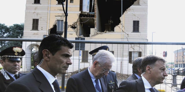 May 22, 2012: Italian Premier Mario Monti, center, looks down as he walks past the damaged town hall of Sant'Agostino, during a visit to the area hit by a quake.