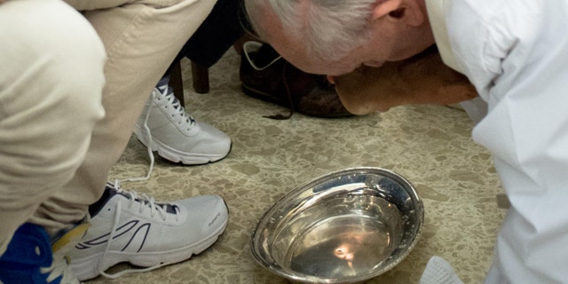 In this photo provided by the Vatican newspaper L'Osservatore Romano, Pope Francis, right, kisses the foot of an inmate at the juvenile detention center of Casal del Marmo, Rome, Thursday, March 28, 2013.