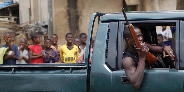 March 12: Children look on as a fighter opposed to Laurent Gbagbo passes in a pick-up truck, in the Anyama neighborhood of Abidjan, Ivory Coast