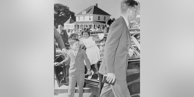 President John F. Kennedy arrives for a 9:00 A.M. Mass at St. Francis Xavier Catholic Church in Hyannis. Following their uncle to the service are (left to right) Christopher Lawford, Maria Shriver, and Sydney Lawford.
