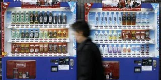 A man walks past vending machines of Asahi Soft Drinks in Tokyo in this December 1, 2008, file photo.