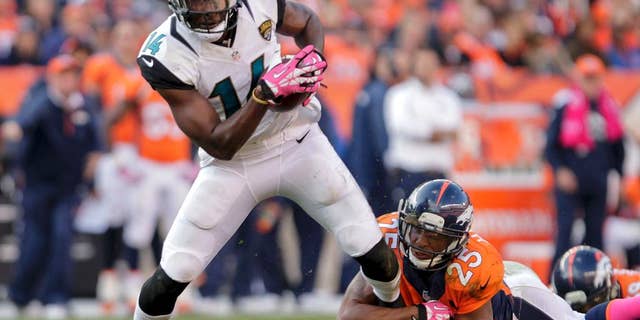 FILE - In this Oct. 13, 2013, file photo, Jacksonville Jaguars wide receiver Justin Blackmon (14) tries to pull away from Denver Broncos cornerback Chris Harris (25) after catching pass during an NFL football game in Denver. Suspended Jaguars receiver Blackmon has checked into a voluntary treatment program and seems to be doing well. Coach Gus Bradley told The Associated Press on Wednesday, Oct. 1, 2014, that the former Oklahoma State star and 2012 first-round NFL draft pick “is doing very well and he’s learning a lot.” Bradley says he is getting updates from Blackmon’s agent. (AP Photo/Joe Mahoney, FIle)