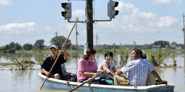 Sept. 11, 2015: Residents paddle a boat past a traffic light in the flooded road in Joso, Ibaraki prefecture, northeast of Tokyo. (Kyodo News via AP)