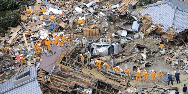 September 4: Volunteer firefighters search destroyed houses for missing people after heavy downpours by Typhoon Talas caused a landslide at Tanabe, central Japan. The storm dumped record amounts of rain Sunday in western and central Japan as it turned towns into lakes, washed away cars and triggered mudslides that obliterated houses.