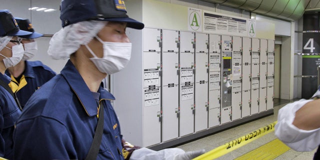 May 31, 2015: Members of the Metropolitan Police Department stand guard near a baggage locker where a suitcase containing the body of an elderly woman was found at Tokyo Station in Tokyo. (Kyodo News via AP)