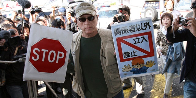 In this Nov. 2, 2010, file photo, Ric O'Barry, a leading global dolphin activist whose efforts to save dolphins is documented in the Oscar-winning film "The Cove," holds "Stop" and "Keep out except persons concerned" signs as he arrives at Taiji Community Center in Taiji, western Japan.