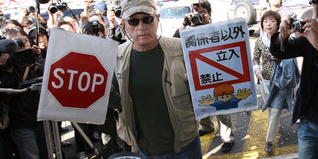 In this Nov. 2, 2010, file photo, Ric O'Barry, a leading global dolphin activist whose efforts to save dolphins is documented in the Oscar-winning film "The Cove," holds "Stop" and "Keep out except persons concerned" signs as he arrives at Taiji Community Center in Taiji, western Japan.