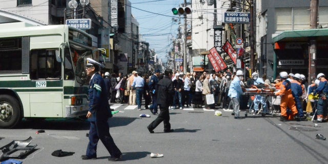 Rescue workers carry an injured person after a car went amok in the Gion district of Kyoto, western Japan, crowded with tourists and cherry blossom viewers Thursday, April 12, 2012. More than a dozen pedestrians were injured, some critically, in the tragedy. (AP Photo/Kyodo News) JAPAN OUT, MANDATORY CREDIT, NO LICENSING IN CHINA, HONG KONG, JAPAN, SOUTH KOREA AND FRANCE