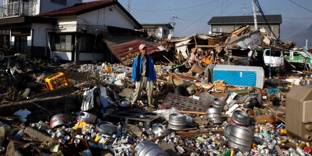 March 13, 2011: A tsunami survivor stands on debris of houses and beer cans and barrels washed away from a nearby brewery factory after the area was hit by Friday's catastrophic earthquake-triggered tsunami in Sendai in Miyagi Prefecture, northern Japan.