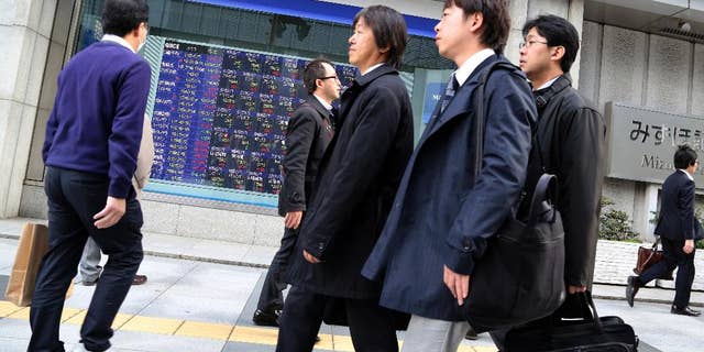 People walk by an electronic stock board of a securities firm in Tokyo, Friday, March 13, 2015. Asian stock markets mostly rose Friday after weak U.S. retail sales alleviated jitters about the Federal Reserve's timetable for raising interest rates. Japan's Nikkei 225 rose 1.4 percent to 19,254.25. (AP Photo/Koji Sasahara)