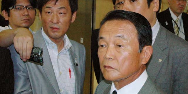 August 1, 2013: Japanese Finance Minister Taro Aso (foreground) is surrounded by reporters at the ministry in Tokyo. Aso has retracted a comment he made Monday suggesting Japan should learn from how the Nazi party stealthily changed Germany’s constitution before World War II before anyone realized it. (AP Photo)