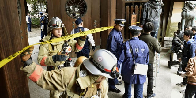 Nov. 23, 2015: Firefighters and police officers inspect around the south gate of Yasukuni shrine in Tokyo after an explosion was reported.  No one was injured.  (Shigeyuki Inakuma/Kyodo News via AP)
