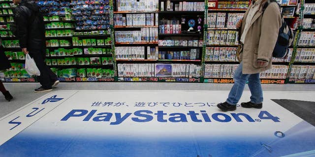 In this Thursday, Dec. 25, 2014 photo, a shopper walks on the logo of Sony's PlayStation 4 at an electronics store in Tokyo. Sony's online PlayStation store and Microsoft's Xbox site suffered disruptions to users on Christmas Day in the latest possible cyber-attacks on the companies. The PlayStation Store Twitter feed said Friday, Dec. 26 that some users were having trouble logging into its network. It said engineers were investigating. (AP Photo/Shizuo Kambayashi)