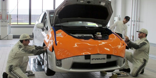 Mechanics work on Prius at a newly completed Toyota's service center in Tajimi, central Japan, Monday, July 22, 2013. Toyota is opening a training facility for mechanics complete with a test course that simulates 13 driving conditions including cobblestones and bumpy roads as part of the automaker's efforts to avoid a repeat of its recall fiasco. (AP Photo/Yuri Kageyama)