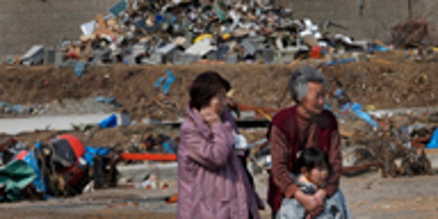 March 31: Survivors watch workers finding victims at the tsunami-destroyed town of Yamada, Iwate Prefecture, northern Japan.