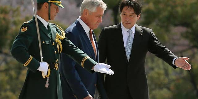 U.S. Secretary of Defense Chuck Hagel, center, is escorted by his Japanese counterpart Itsunori Onodera, right, as they inspect an honor guard at the Defense Ministry in Tokyo, Sunday, April 6, 2014. Against the backdrop of Russia's takeover of Ukraine's Crimean region, Hagel said Saturday he will convey to Japanese leaders that the U.S. is strongly committed to protecting their country's security. (AP Photo/Eugene Hoshiko)
