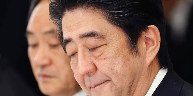 In this Wednesday, Feb. 25, 2015 photo, Japanese Prime Minister Shinzo Abe bites his lips during a meeting with a panel of experts at his official residence in Tokyo. Abe convened the experts to advise him on what to say to mark the 70th anniversary of the end of World War II on Aug. 15. A tug-of-war has emerged between those who want Abe to stick to the apologies made by past prime ministers for Japan's wartime aggression and colonial rule, and those who say such accounts are exaggerated or even fabricated. Abe, known for harboring revisionist views, must strike a balance, as any statement viewed as watering down past apologies would anger China and South Korea and displease the United States too. Behind Abe is government spokesman Chief Cabinet Secretary Yoshihide Suga. (AP Photo/Shizuo Kambayashi)