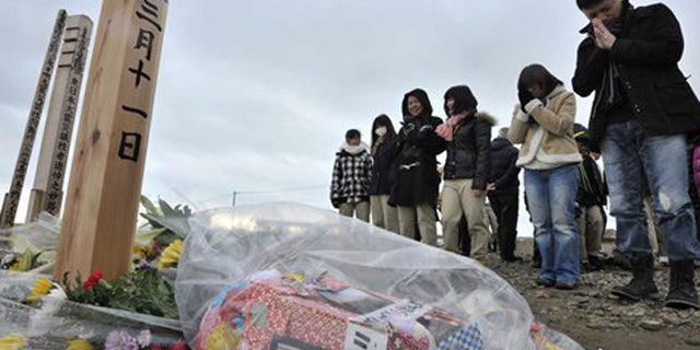 Mar. 11, 2012: People offer prayers to mourn the victims of the March 11, 2011 earthquake and tsunami on a hill in Natori, Miyagi prefecture, Japan.